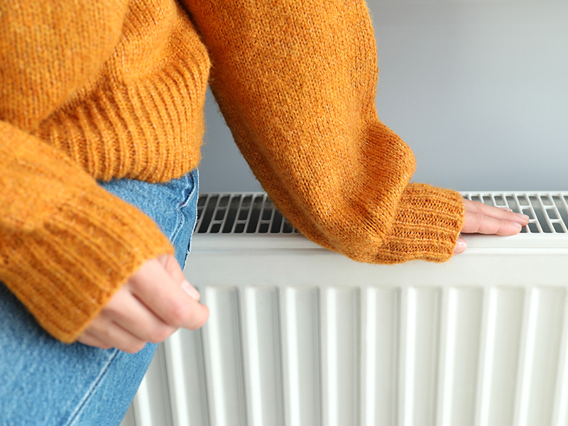 En person i orange vintertröja sitter på ett element.
