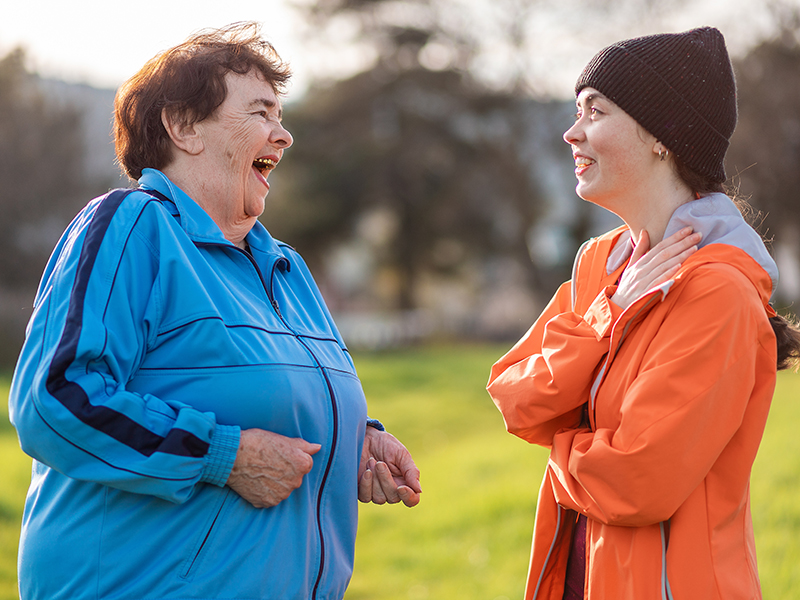 En äldre och en yngre kvinna pratar med varandra utomhus.
