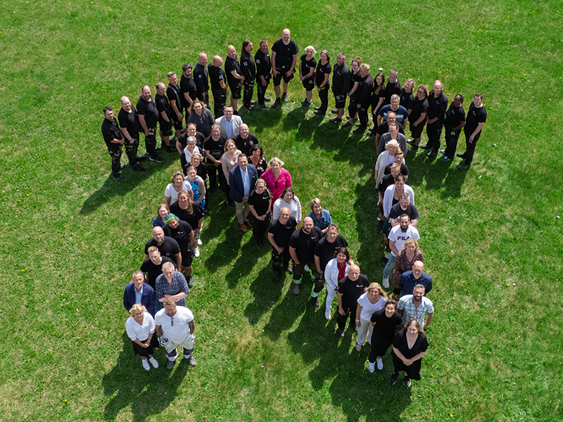 Gruppbild på Nyköpingshems personal som tillsammans bildar ett stort N.