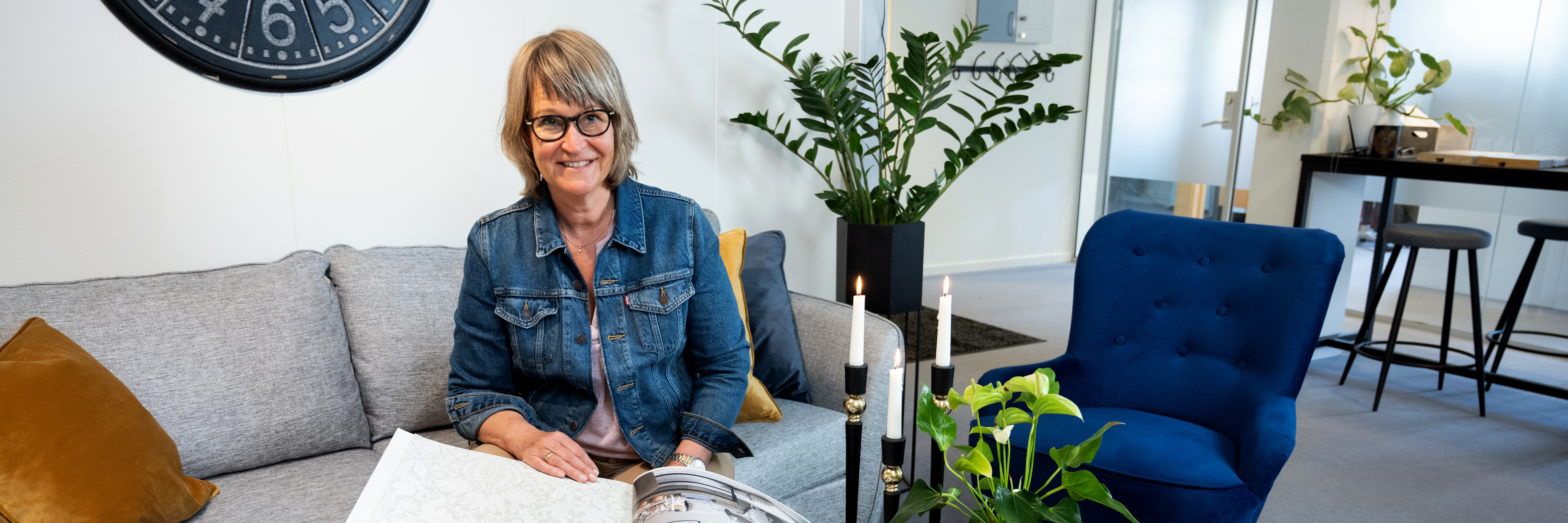 Kundvärden Helene sitter i en grå besökssoffa  i kundcnter och visar tapetprover.