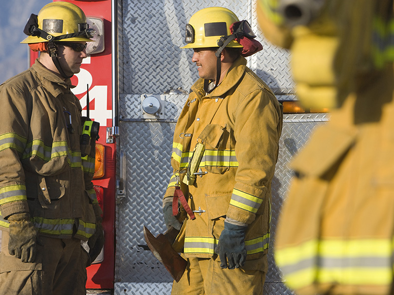 Tre brandmän vid ett utryckningsfordon.