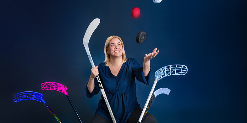 Malin Lehnbom jonglerar bollar och puckar i olika färger och har flera innebandyklubbor och hockeyklubbor framför sig.